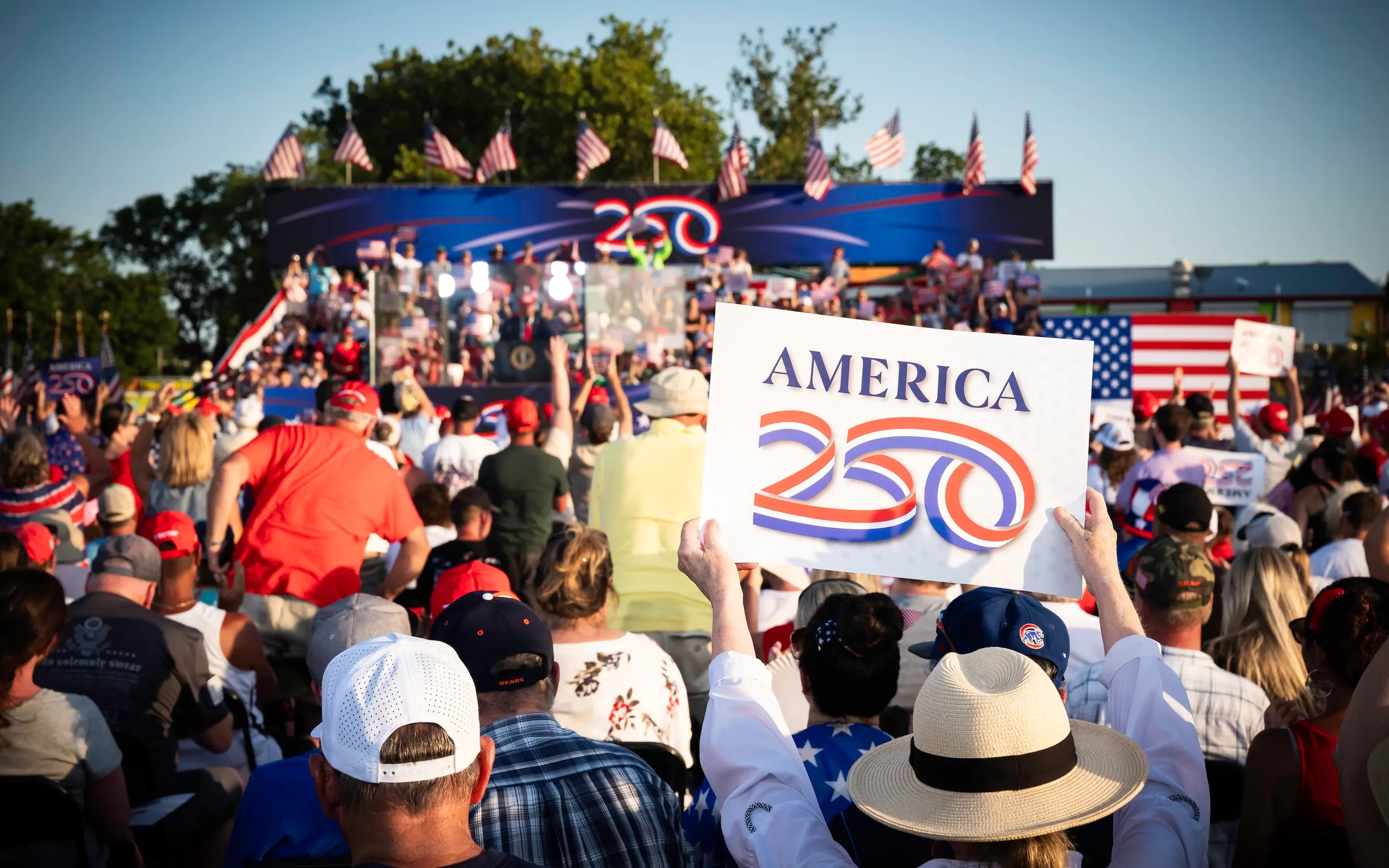 Woman holding America250 sign as President Trump gives speech at the America250 Iowa event on July 3 2025